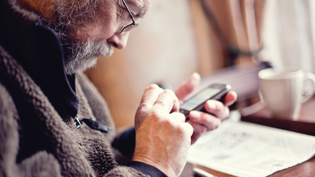 Een man kijkt op zijn GSM.